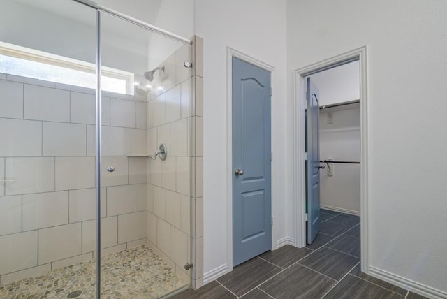 full bathroom featuring a walk in closet, baseboards, and a stall shower