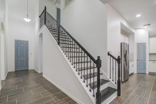 stairs with baseboards, visible vents, arched walkways, and wood finish floors