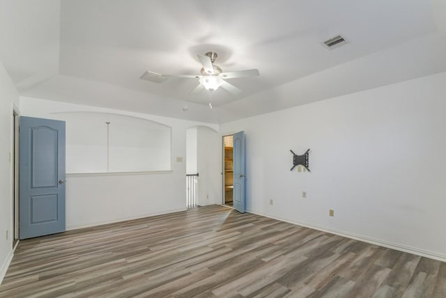 spare room featuring a ceiling fan, wood finished floors, visible vents, and baseboards