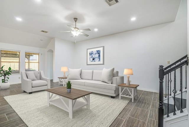 living room featuring stairway, arched walkways, visible vents, and baseboards