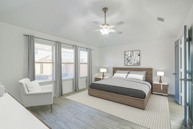 bedroom with visible vents, baseboards, ceiling fan, light wood-type flooring, and vaulted ceiling