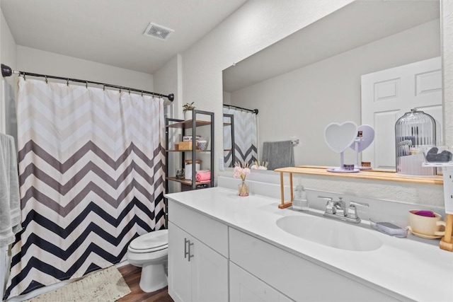 bathroom featuring visible vents, toilet, vanity, and wood finished floors