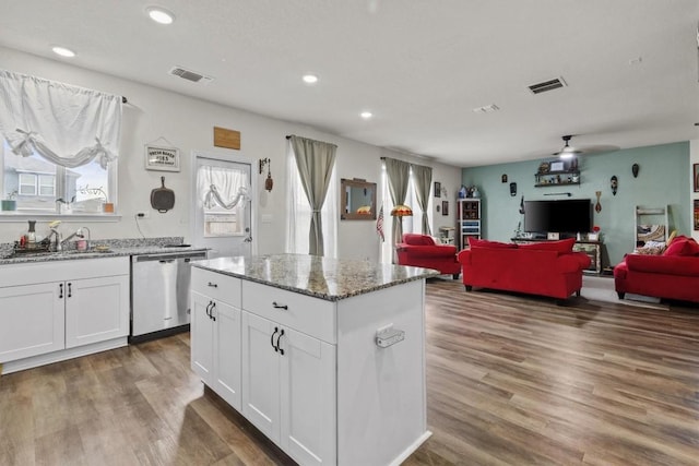 kitchen featuring visible vents, open floor plan, stainless steel dishwasher, wood finished floors, and a sink