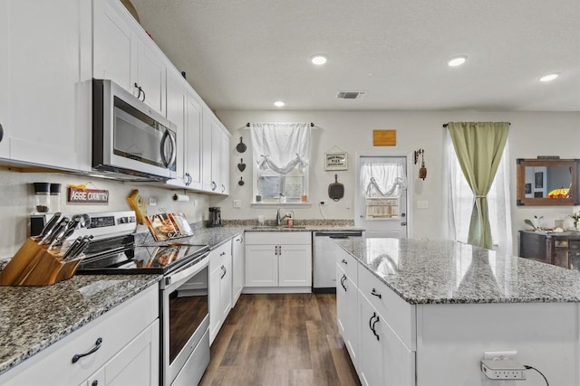 kitchen featuring a sink, dark wood finished floors, a center island, stainless steel appliances, and white cabinets