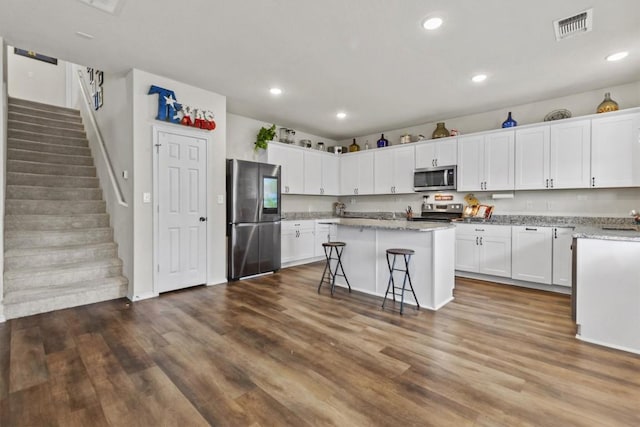 kitchen featuring visible vents, dark wood finished floors, a center island, white cabinetry, and appliances with stainless steel finishes