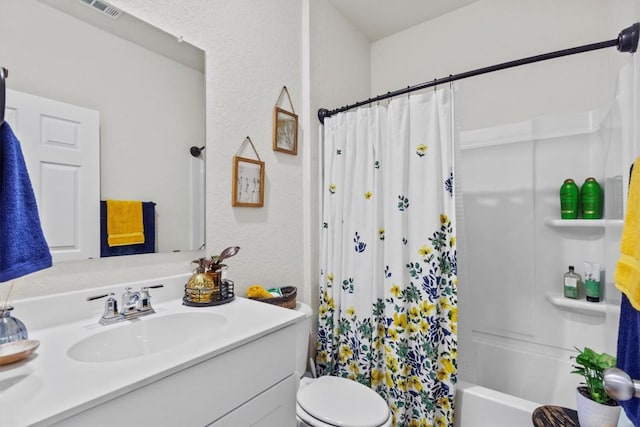 full bathroom featuring vanity, visible vents, toilet, a textured wall, and shower / tub combo with curtain