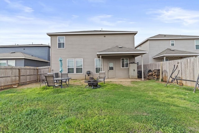 back of house with a lawn, an outdoor fire pit, and a fenced backyard