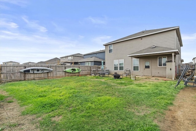 rear view of house featuring a fenced backyard, a lawn, and a fire pit