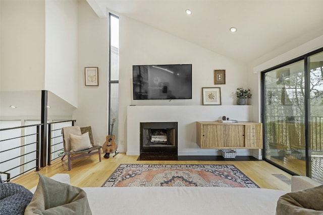 living area with visible vents, a fireplace with flush hearth, lofted ceiling, recessed lighting, and wood finished floors