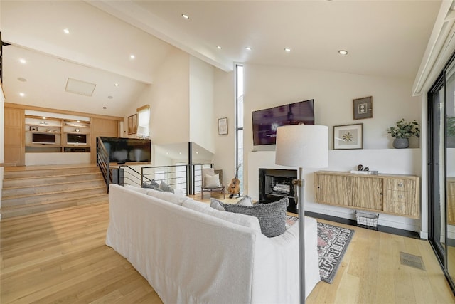 living room with visible vents, light wood-type flooring, recessed lighting, a fireplace, and high vaulted ceiling