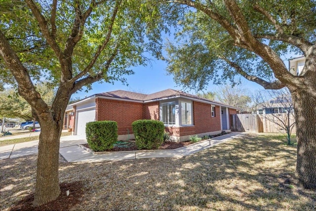 view of side of home featuring brick siding, a garage, and fence