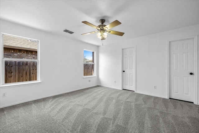 unfurnished bedroom featuring carpet flooring, ceiling fan, baseboards, and visible vents