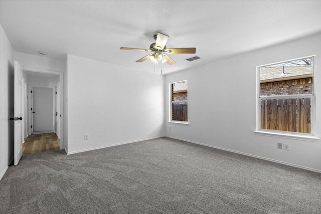 spare room featuring visible vents, plenty of natural light, ceiling fan, and carpet flooring