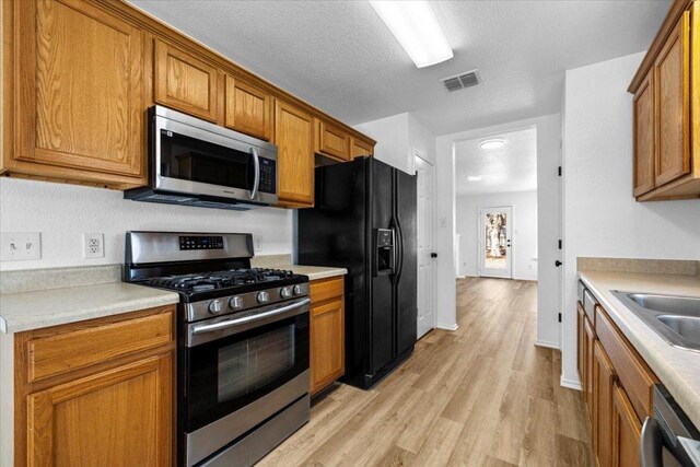 kitchen featuring visible vents, brown cabinets, appliances with stainless steel finishes, and light countertops