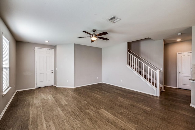 empty room featuring visible vents, stairway, baseboards, ceiling fan, and dark wood-style flooring