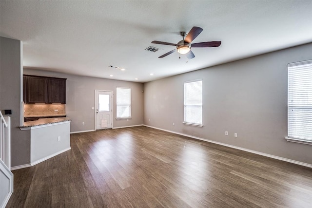 unfurnished living room with a ceiling fan, visible vents, baseboards, and dark wood-style flooring