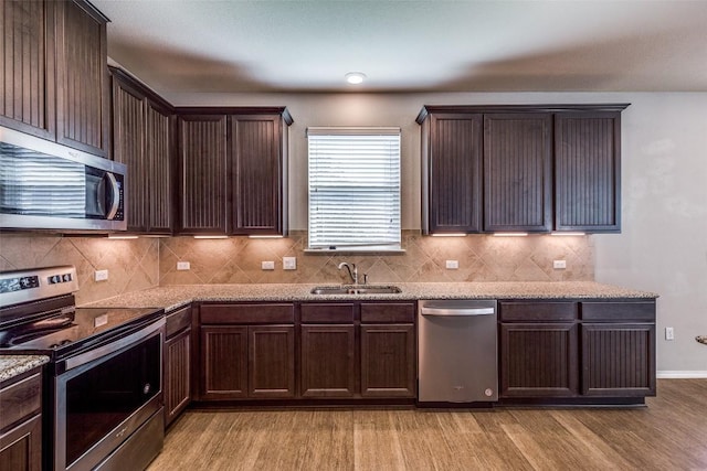 kitchen featuring dark brown cabinetry, light wood-style floors, appliances with stainless steel finishes, and a sink