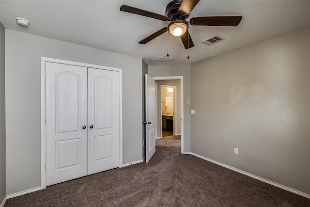 unfurnished bedroom with a closet, visible vents, dark carpet, and baseboards