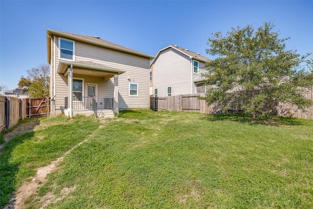 rear view of house with a lawn and a fenced backyard