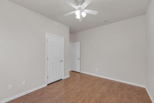 spare room with visible vents, baseboards, and wood finished floors