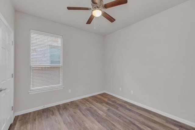 spare room featuring baseboards, wood finished floors, and a ceiling fan