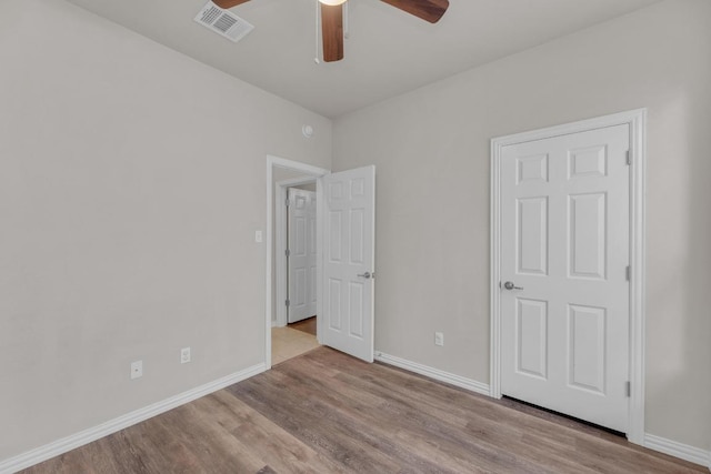 unfurnished bedroom featuring visible vents, baseboards, wood finished floors, and a ceiling fan