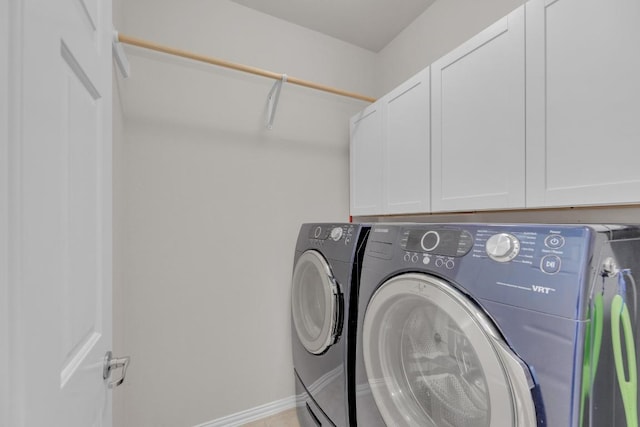 laundry area featuring baseboards, cabinet space, and washing machine and clothes dryer