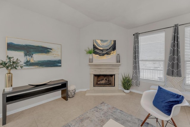 living area featuring tile patterned flooring, lofted ceiling, a fireplace with raised hearth, and baseboards