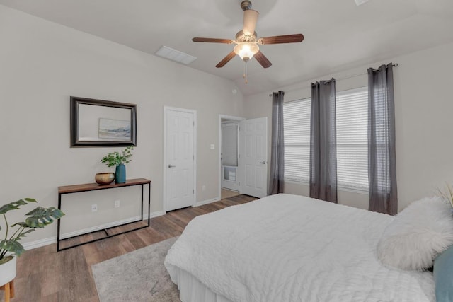 bedroom with lofted ceiling, wood finished floors, visible vents, and baseboards