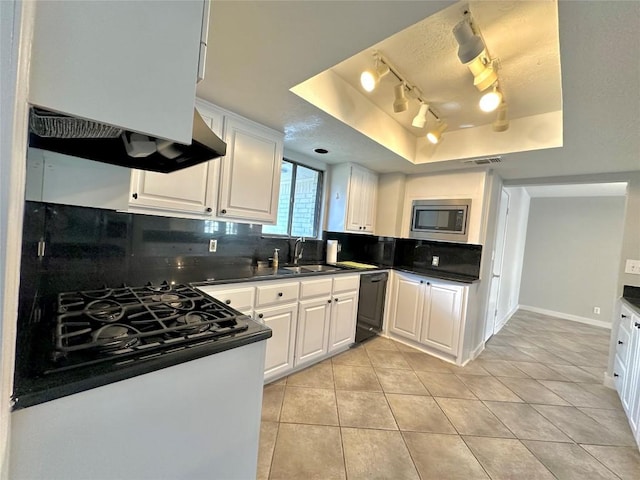 kitchen with tasteful backsplash, dark countertops, black dishwasher, light tile patterned floors, and a raised ceiling