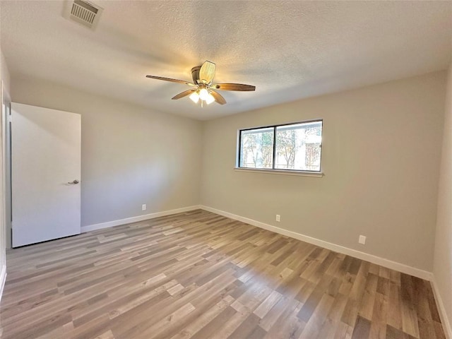 spare room featuring ceiling fan, light wood-style floors, baseboards, and a textured ceiling