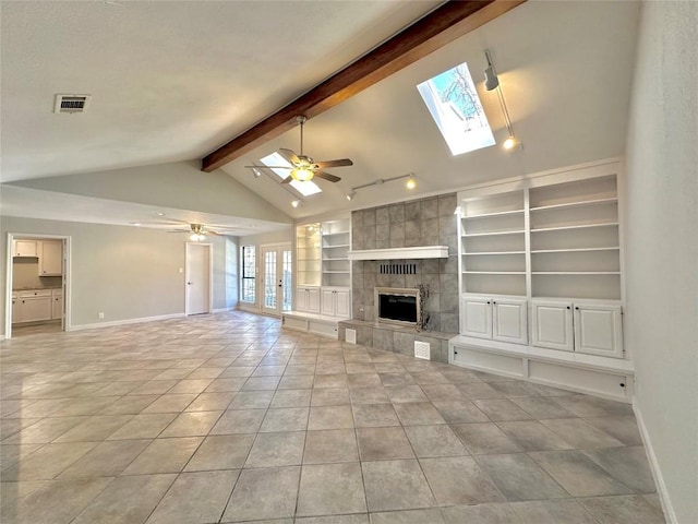 unfurnished living room featuring visible vents, lofted ceiling with skylight, a ceiling fan, a fireplace, and baseboards