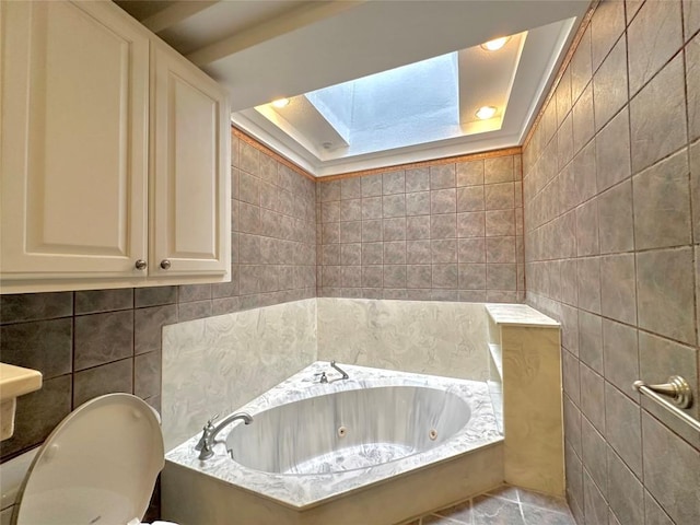 full bathroom with a jetted tub, toilet, tile walls, and a skylight