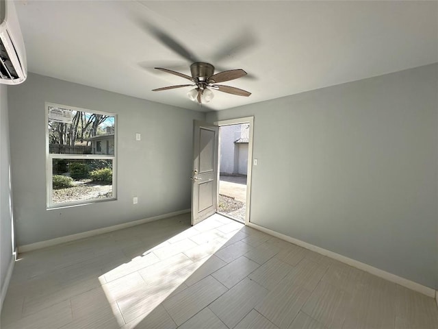 spare room with baseboards, ceiling fan, and a wall mounted AC