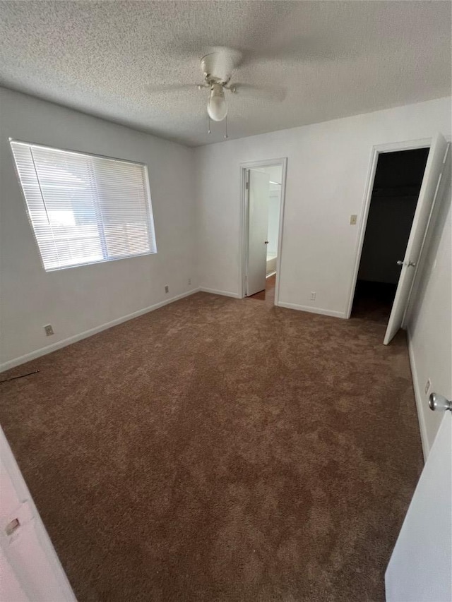 unfurnished bedroom featuring a ceiling fan, baseboards, carpet floors, ensuite bathroom, and a textured ceiling