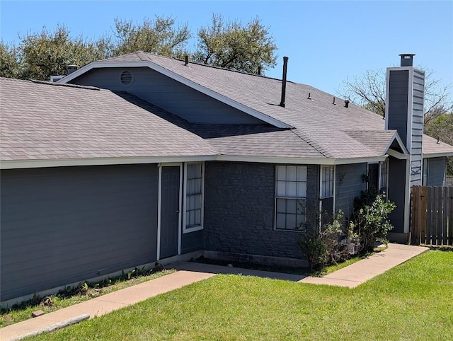 exterior space featuring a chimney, a front yard, fence, and roof with shingles