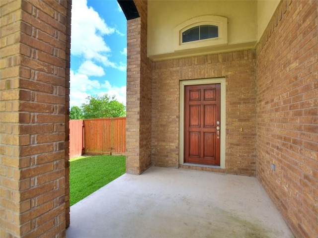 doorway to property featuring a patio area, fence, and brick siding