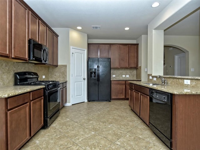 kitchen featuring light stone countertops, visible vents, a sink, black appliances, and tasteful backsplash