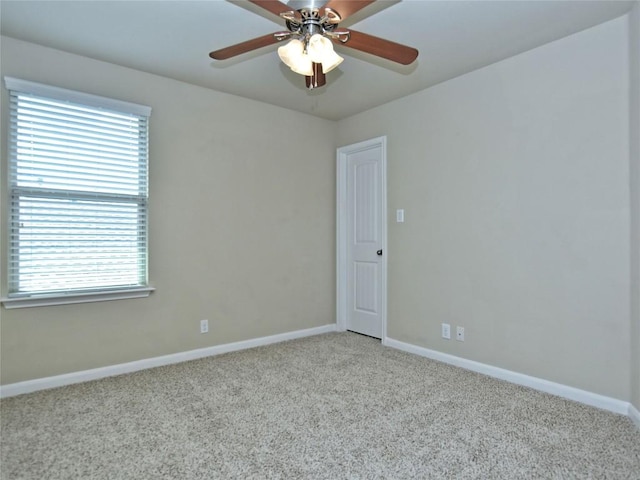 empty room featuring a ceiling fan, light colored carpet, and baseboards