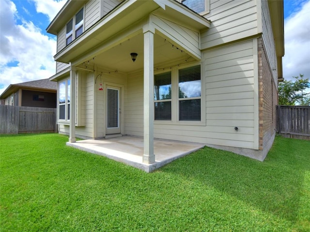 rear view of house with a yard, a patio, brick siding, and a fenced backyard