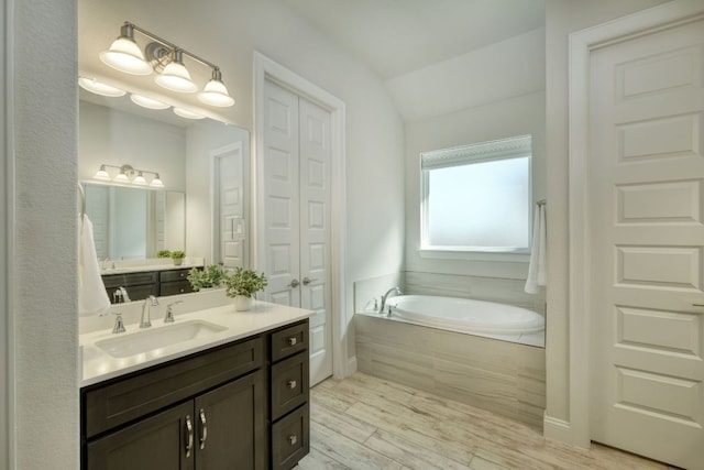 full bathroom with lofted ceiling, a garden tub, wood finished floors, a closet, and vanity