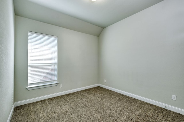 unfurnished room featuring lofted ceiling, baseboards, and dark carpet