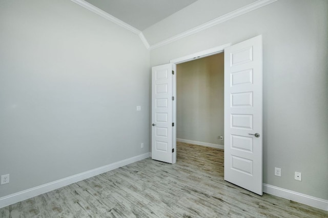 unfurnished bedroom featuring baseboards, wood finished floors, ornamental molding, and vaulted ceiling