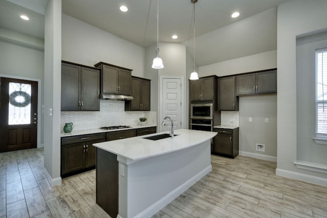 kitchen with a sink, dark brown cabinetry, appliances with stainless steel finishes, and under cabinet range hood