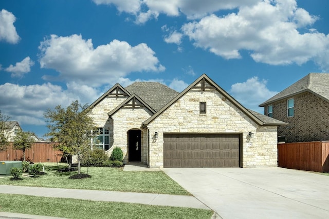 french provincial home featuring fence, driveway, an attached garage, a shingled roof, and a front lawn