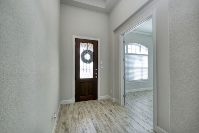 foyer with light wood-type flooring, baseboards, and a textured wall