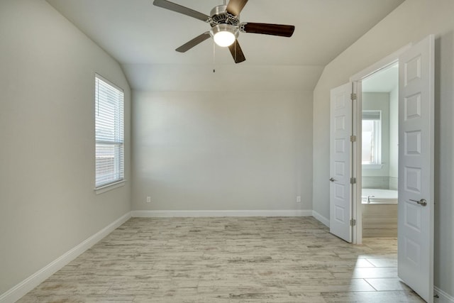 empty room with light wood-type flooring, baseboards, a ceiling fan, and vaulted ceiling