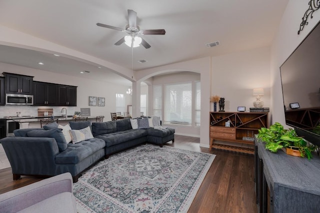 living area featuring visible vents, dark wood-type flooring, recessed lighting, arched walkways, and a ceiling fan