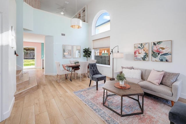 living area with visible vents, a high ceiling, baseboards, and wood finished floors