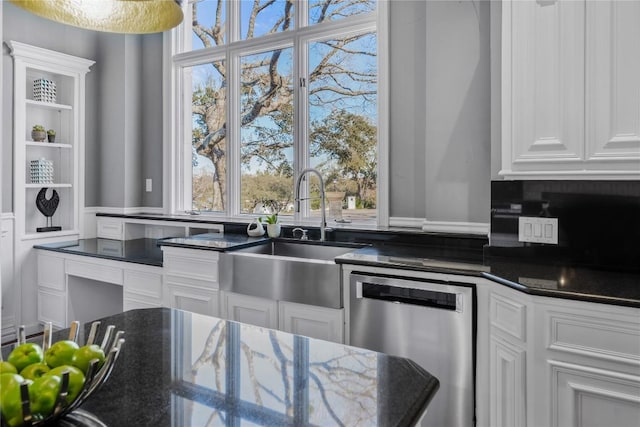 kitchen with dishwasher, dark stone counters, white cabinetry, and a sink